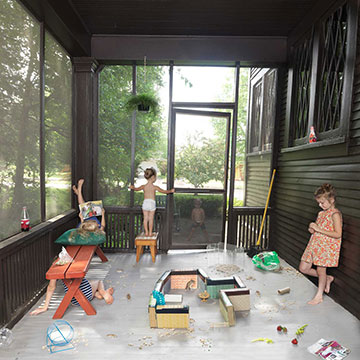 photograph of four young children engaged in various activities on a screened in porch